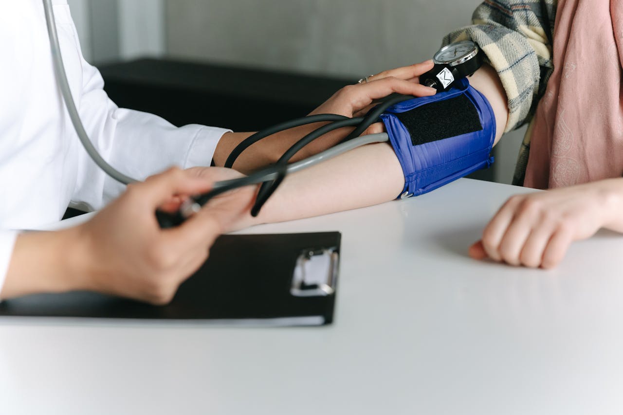who-we-are A healthcare worker uses a sphygmomanometer to check a patient's blood pressure in a medical office.